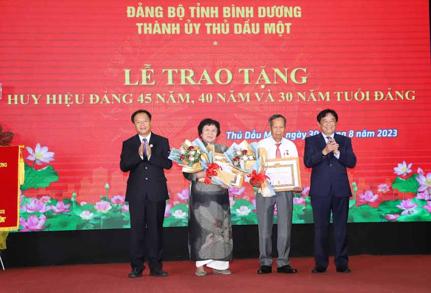 8; Ông Nguyễn Hoàng Thao và ông Nguyễn Văn Đông, Ủy viên Thường vụ Tỉnh ủy, Bí thư Thành ủy Thủ Dầu Một trao tặng Huy hiệu 45 năm tuổi Đảng cho các đảng viê